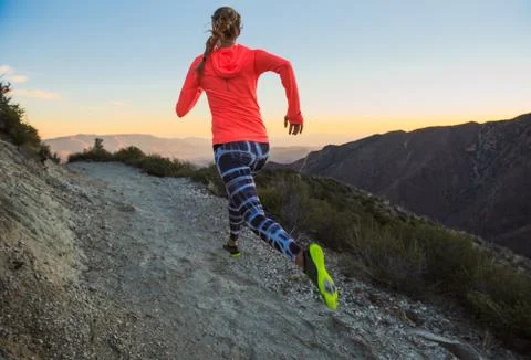 Rear view of young woman trail running on dirt track at dusk on Pacific Crest Stock Photos