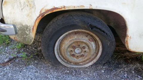 Rear wheel well with flat ruptured and torn tire on rusty abandoned derelict car Stock Footage 167525621