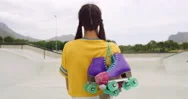 Rearview Of A Female Roller Skater Carrying Skates In A Skate Park. A Cool Urban Stock Footage
