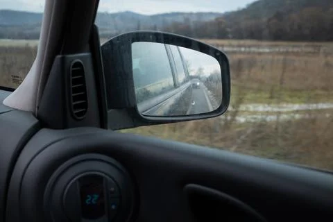 Rearview mirror reflection of nature set against a beautiful winter scenery. Stock Photos