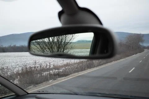 Rearview mirror reflection of nature set against a beautiful winter scenery. Stock Photos