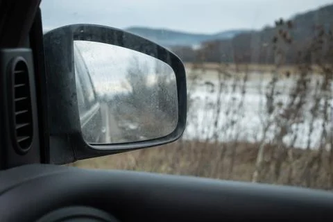 Rearview mirror reflection of nature set against a beautiful winter scenery. Stock Photos