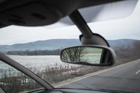 Rearview mirror reflection of nature set against a beautiful winter scenery. Stock Photos