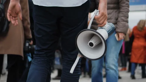 Rebel go on strike through crowd and holds in hand a megaphone or loudspeaker. Stock Footage 96079478