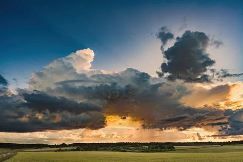 A receding layer of storm clouds over a tranquil landscape at sunset 写真素材