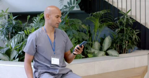 Receiving call, African man in grey scrubs checking smartphone, coordinating Stock Footage 341241150