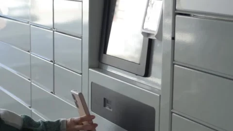 Receiving a parcel from an automated terminal. The woman's hand puts the phone Stock Footage 297460959
