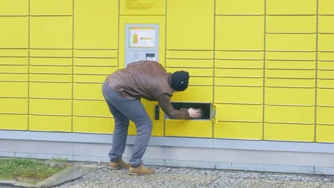 Receiving a parcel out of an automated packstation in germany 動画素材 83677600
