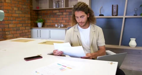 Receiving printed pages, man in 20s reading, comparing and sorting documents at Stock Footage 342065346
