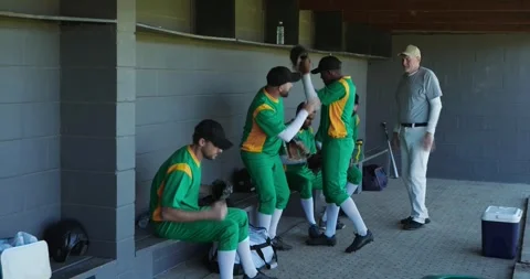 Receiving water bottle diverse baseball team preparing for game in dugout, with Stock Footage 340964114