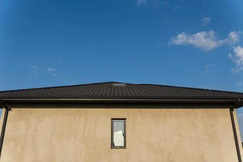 A recently built home features a smooth plaster exterior and a dark tiled r.. 库存照片