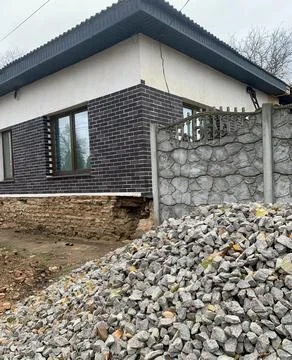 A recently built house features a brick facade and a stone boundary wall. A Foto stock