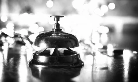 Reception bell on the table and shining garland background Stock Photos