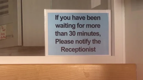 Reception Sign Advising Visitors to Report Waiting Over Thirty Minutes Stock Footage 344474244