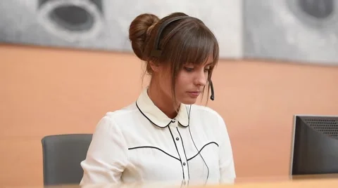Receptionist at front desk with headset on Stock Footage 64734001