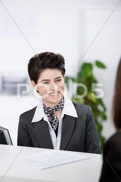 Receptionist looking at customer at counter Stock Photos