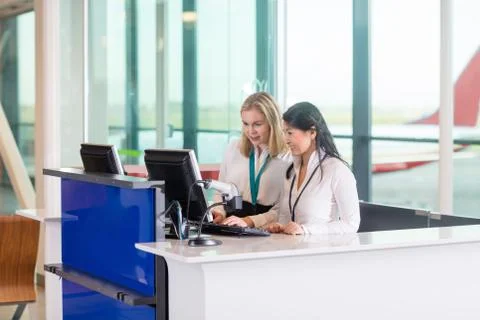 Receptionists Using Computer At Counter In Airport 写真素材