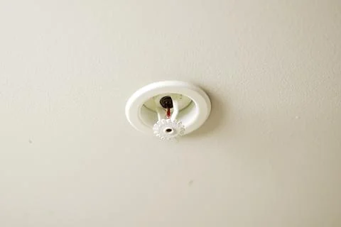 Recessed automatic fire sprinkler head installed on a white plaster ceiling Stock Photos