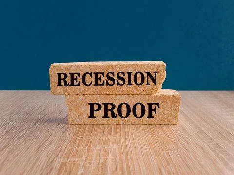 RECESSION PROOF text on brick blocks. Beautiful wooden table Stock Photos