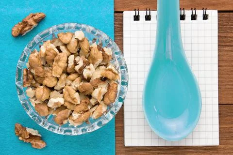 Recipe notebook with walnuts on a blue background and a wooden board. Stock Photos