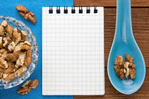 Recipe notebook with walnuts on a blue background and a wooden board. Stock Photos