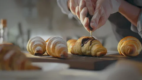 Recipe. A professional baker dressed in an apron decorates croissant with ch Stock Footage 274167798