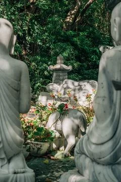 Reclining Buddha statue viewed between seated Buddhist figures and tropical Foto stock