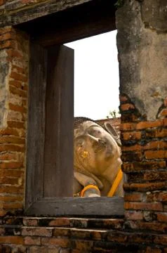 Reclining buddha, view through a window with a wooden frame onto his face. Stock Photos