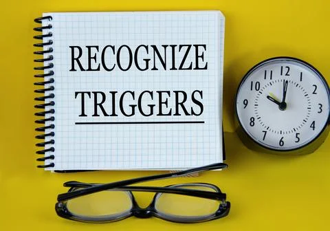 RECOGNIZE TRIGGERS - words in a white notebook with alarm clock and magnify.. Stock Photos