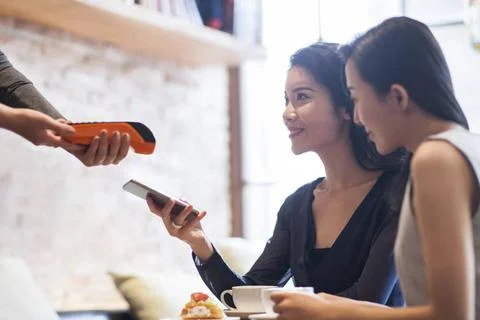 RECORD DATE NOT STATED Chinese friends paying with smart phone in cafÃ Bei.. Stock Photos