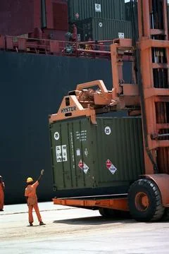 RECORD DATE NOT STATED A dock worker guides the operator of a container li... Stock Photos