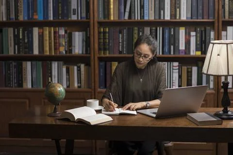 RECORD DATE NOT STATED Elegant mature Chinese woman using laptop in study ... 스톡 사진