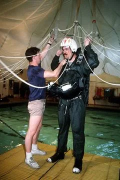 RECORD DATE NOT STATED An instructor helps an aviator put on a parachute h... Stock Photos