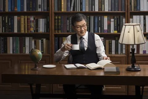 RECORD DATE NOT STATED Senior Chinese businessman reading book in study Be... 스톡 사진