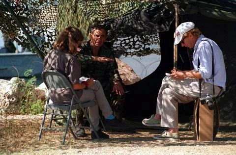 RECORD DATE NOT STATED Under the shade of camouflage netting, two civilian... 스톡 사진
