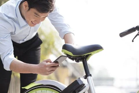 RECORD DATE NOT STATED Young Chinese man scanning a QR code to unlock a sh... Stock-Fotos