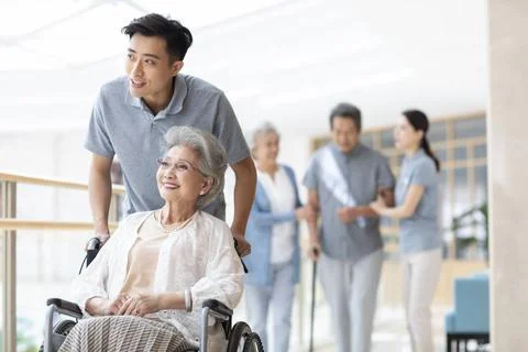 RECORD DATE NOT STATED Young Chinese nurse assistant taking care of senior... Stock Photos