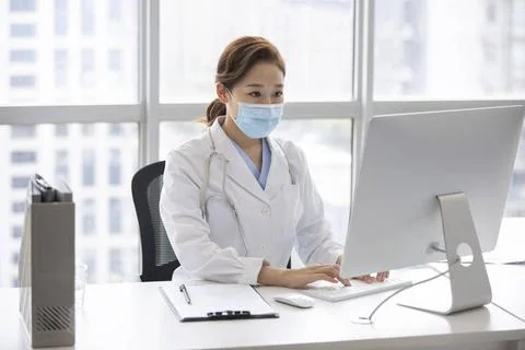 RECORD DATE NOT STATED Young Chinese doctor using computer in doctor s off... Stock Photos