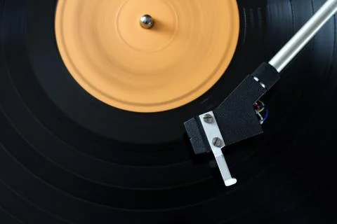Record player stylus on a rotating disc with orange label Stock Photos