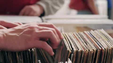 At the record store, customers browse vinyl records in plastic bins, exploring a Stock Footage 277417880