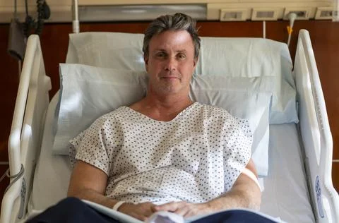 Recovering man making eye contact from hospital bed Stock Photos