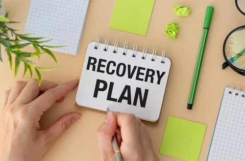 Recovery Plan text on notebook and hands on yellow background Stock Photos