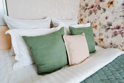 Rectangle bed with white linens, green pink pillows in creative arts pattern 스톡 사진