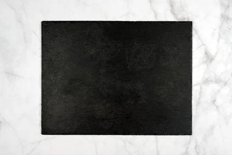 Rectangle black slate stone cutting board, empty signboard on light marble ba 스톡 사진