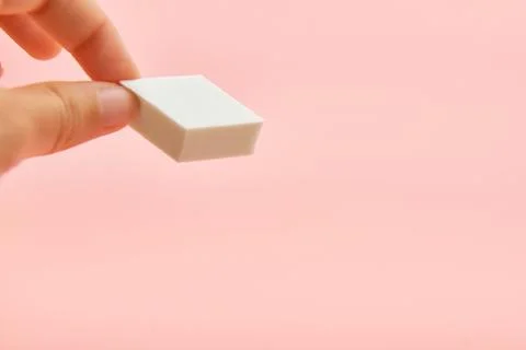 Rectangle cosmetic white sponge in hands on pink background, copy space, beauty Stock Photos