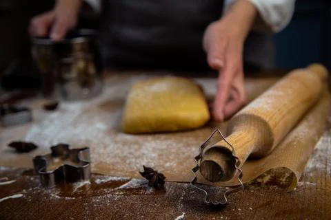 A rectangle of dough lies on baking parchment, a rolling pin and cookie cutters Stock Photos
