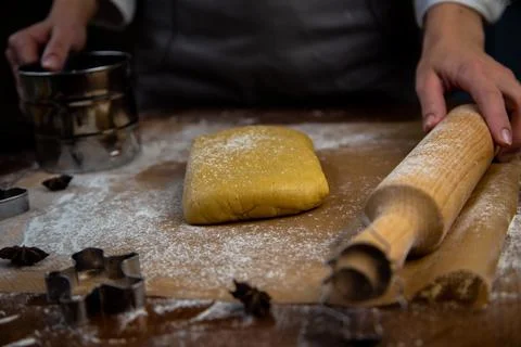 A rectangle of dough lies on baking parchment, a rolling pin and cookie cutters Stock Photos