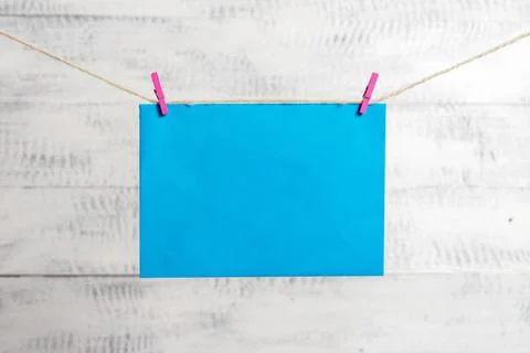 Rectangle shaped note colored paper clipped in a clothesline by clothespin... Stock Photos