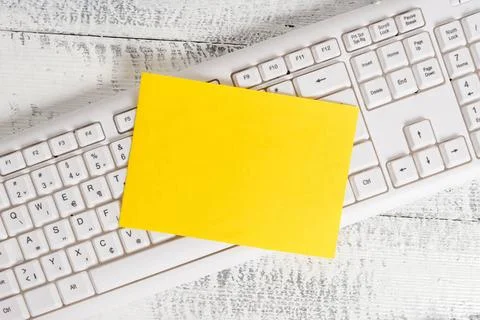 Rectangle shaped note colored paper in a keyboard and a white wooden backg... Stock Photos