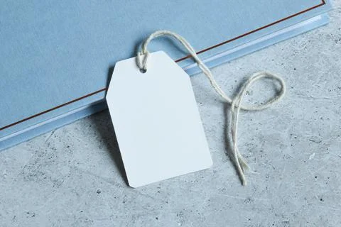 Rectangle white gift tag mockup with white card on blue book and grey background Stock Photos